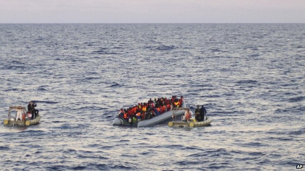 Rescue crews approach migrants on a rubber boat some 40 miles (65 kilometers) from the Libyan capital, Tripoli, in 2014