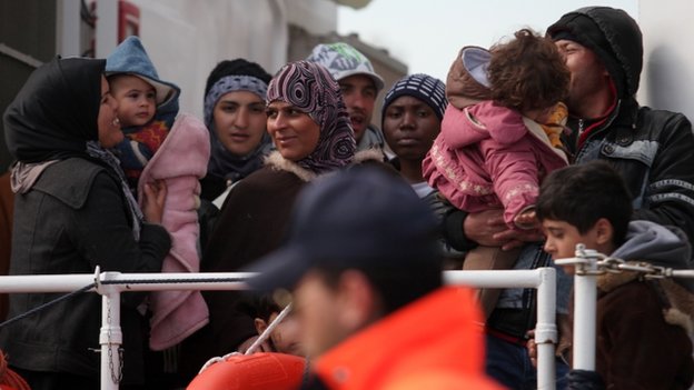 Rescued migrants wait to disembark from an Italian Coast Guard vessel 