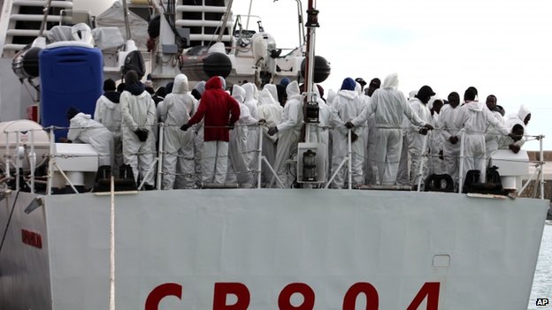 Migrants await to disembark from an Italian ship