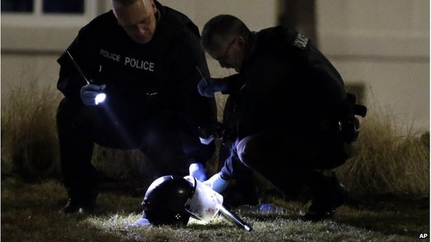 Police examine helmet lying on ground after two officers were shot in Ferguson, Missouri, 12 March 2016